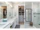 Bathroom showcasing double vanity, walk-in closet, and glass-enclosed shower with modern fixtures and finishes at 15752 Sacile Ln, Bradenton, FL 34211