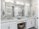 Bright bathroom featuring double sinks with white cabinets and drawers, and a large well-lit mirror at 15752 Sacile Ln, Bradenton, FL 34211