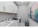 Well-lit laundry room with white cabinets, front-load washer and dryer, and utility sink at 15752 Sacile Ln, Bradenton, FL 34211