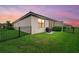 Home backyard featuring a fenced-in yard, green grass, and a barbecue grill under a lovely pink sky at 16012 Sunny Day Dr, Bradenton, FL 34211