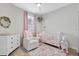 Charming Bedroom with a white crib, rocking chair, dresser, and floral accents at 16012 Sunny Day Dr, Bradenton, FL 34211