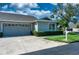 Charming home featuring a two-car garage and front yard with mature trees and lush landscaping at 1612 Fairway Oaks Dr, Palmetto, FL 34221