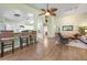 Open-concept living room with wood-look tile flooring, ceiling fan, and adjacent kitchen with counter seating at 1612 Fairway Oaks Dr, Palmetto, FL 34221