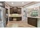 Open kitchen with a built-in desk, dark wood cabinets, stainless steel fridge, granite countertops, and wood-look tile flooring at 16246 26Th E St, Parrish, FL 34219
