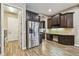Kitchen with stainless steel refrigerator, dark cabinets, built-in desk, and wood-look tile flooring at 16246 26Th E St, Parrish, FL 34219
