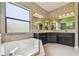 Luxurious bathroom with a large soaking tub, tile surround, double sink vanity, and ample natural light at 16246 26Th E St, Parrish, FL 34219