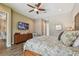 Bright bedroom with wood flooring, ceiling fan, and a flat-screen television mounted above a wooden dresser at 16246 26Th E St, Parrish, FL 34219