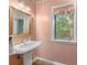 Charming bathroom featuring classic fixtures, a pedestal sink, and patterned wallpaper at 1671 South Dr, Sarasota, FL 34239