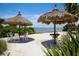 Relaxing beach area with tiki umbrellas and tables overlooking the water at 262 Sapphire Lake Dr # 202, Bradenton, FL 34209