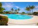 The community pool is surrounded by a lush tropical landscape with lounge chairs and clear blue skies at 262 Sapphire Lake Dr # 202, Bradenton, FL 34209