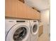 Convenient laundry room featuring a Whirlpool washer and dryer and wooden cabinets at 301 Quay Commons # 1208, Sarasota, FL 34236