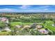 High aerial view showcasing houses with red tiled roofs surrounded by lush landscaping, golf course and lake at 3388 Highlands Bridge Rd, Sarasota, FL 34235