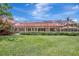 View of the back of the home with a screened in lanai overlooking a manicured lawn at 3388 Highlands Bridge Rd, Sarasota, FL 34235