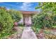Charming front entrance surrounded by lush greenery and colorful flowers at 3388 Highlands Bridge Rd, Sarasota, FL 34235