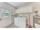 Functional laundry room with storage cabinets, washer, dryer, and easy outdoor access at 3707 Kingswood Dr, Sarasota, FL 34232