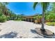 Large paver driveway leading to a three-car garage and lush, mature landscaping at 4647 Stone Ridge Trl, Sarasota, FL 34232