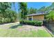 Side view of a tan home with a lush lawn, garden, and black fence at 4647 Stone Ridge Trl, Sarasota, FL 34232