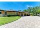 Three-car garage with a paver driveway, solar panels, and well-maintained lawn at 4647 Stone Ridge Trl, Sarasota, FL 34232