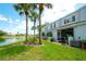 Lush backyard with lake view, tall palm trees, and screened-in patio overlooking the lawn at 4727 Sabal Key Dr # 4727, Bradenton, FL 34203