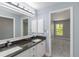 Bright bathroom with double vanity, granite countertops, and updated fixtures, adjoined to carpeted room with bright natural lighting at 5266 Wagon Wheel Dr, North Port, FL 34291