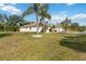 Well-maintained home featuring a lush lawn, mature palm trees, and an extended driveway leading to the garage at 5266 Wagon Wheel Dr, North Port, FL 34291