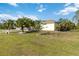 Residential property with a well-manicured lawn, tropical trees, and a bright yellow exterior at 5266 Wagon Wheel Dr, North Port, FL 34291