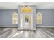 Elegant foyer featuring new gray wood flooring, soft blue walls, decorative light fixture and arched windows flanking front door at 5266 Wagon Wheel Dr, North Port, FL 34291