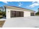 Exterior shot of the garage with white walls, roll up doors, and a wide concrete driveway at 5266 Wagon Wheel Dr, North Port, FL 34291