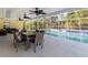 Covered outdoor dining area with wicker chairs, a glass-top table, and ceiling fans, situated beside a sparkling pool at 5266 Wagon Wheel Dr, North Port, FL 34291