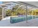 A sparkling blue pool surrounded by a white screened enclosure, with lush landscaping providing privacy at 5266 Wagon Wheel Dr, North Port, FL 34291