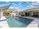 Clear, blue pool in a screened enclosure, reflecting the sky and surrounded by lush landscaping and a patio at 5266 Wagon Wheel Dr, North Port, FL 34291