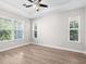 Well-lit bedroom with a ceiling fan, hardwood floors, and large windows offering natural light at 5709 Wild Sage Cir, Sarasota, FL 34238