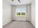 Bedroom with neutral carpet and a window overlooking the manicured lawn at 5709 Wild Sage Cir, Sarasota, FL 34238