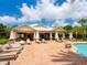 A covered pool-side lounge area with tables, chairs, and lounge seating offers respite from the summer sun at 5709 Wild Sage Cir, Sarasota, FL 34238