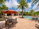Community pool area with lounge chairs, tables, umbrellas, and lush tropical landscaping at 5709 Wild Sage Cir, Sarasota, FL 34238