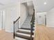Carpeted staircase with dark wood and iron railings, connecting to the light hardwood flooring in the entry area at 5709 Wild Sage Cir, Sarasota, FL 34238