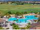 Expansive aerial view of a community pool area with lush landscaping, waterfalls, and golf course views, offering resort-style living at 5843 Wake Forest Run # 104, Bradenton, FL 34211