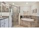 Bathroom with soaking tub and glass shower, framed by neutral tiling at 5843 Wake Forest Run # 104, Bradenton, FL 34211