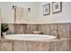 Close-up on a soaking tub with decorative accents and neutral tile surround in this bathroom at 5843 Wake Forest Run # 104, Bradenton, FL 34211