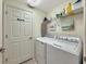 Laundry room with side-by-side washer and dryer, wire shelving, and a door to the hallway at 5843 Wake Forest Run # 104, Bradenton, FL 34211