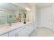 Bathroom featuring double sinks, white cabinets, and a decorative light fixture at 7136 Summerland Cv, Bradenton, FL 34202