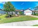 Inviting single-story home showcasing lush landscaping, mature trees, and an attached two-car garage at 7136 Summerland Cv, Bradenton, FL 34202