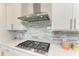 Close up on the gourmet cooktop features a modern hood and elegant backsplash at 7136 Summerland Cv, Bradenton, FL 34202