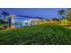 Nighttime view of the backyard with a pool, screened enclosure, lush lawn, and mature landscaping, perfect for outdoor living at 7817 Alhambra Dr, Bradenton, FL 34209
