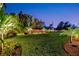 Backyard featuring an illuminated privacy fence, lush landscaping, and a well-manicured lawn, perfect for evening enjoyment at 7817 Alhambra Dr, Bradenton, FL 34209