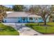 Charming light blue home with a well manicured lawn, curved driveway and welcoming front porch with blue seating at 7817 Alhambra Dr, Bradenton, FL 34209