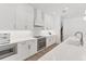 Modern white kitchen featuring stainless steel appliances, sleek countertops, and hardwood floors at 8069 Tidal Pointe Way, Sarasota, FL 34240