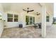 Covered outdoor patio with ceiling fans, stone tile flooring, and comfortable seating area at 8069 Tidal Pointe Way, Sarasota, FL 34240