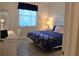 Bedroom with a blue bed, patterned throw, desk and bedside table with a lamp by the window at 8755 Olde Hickory Ave # 7107, Sarasota, FL 34238