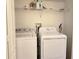 Bright laundry room includes a white washer and dryer, shelving, and hook for a broom at 8755 Olde Hickory Ave # 7107, Sarasota, FL 34238